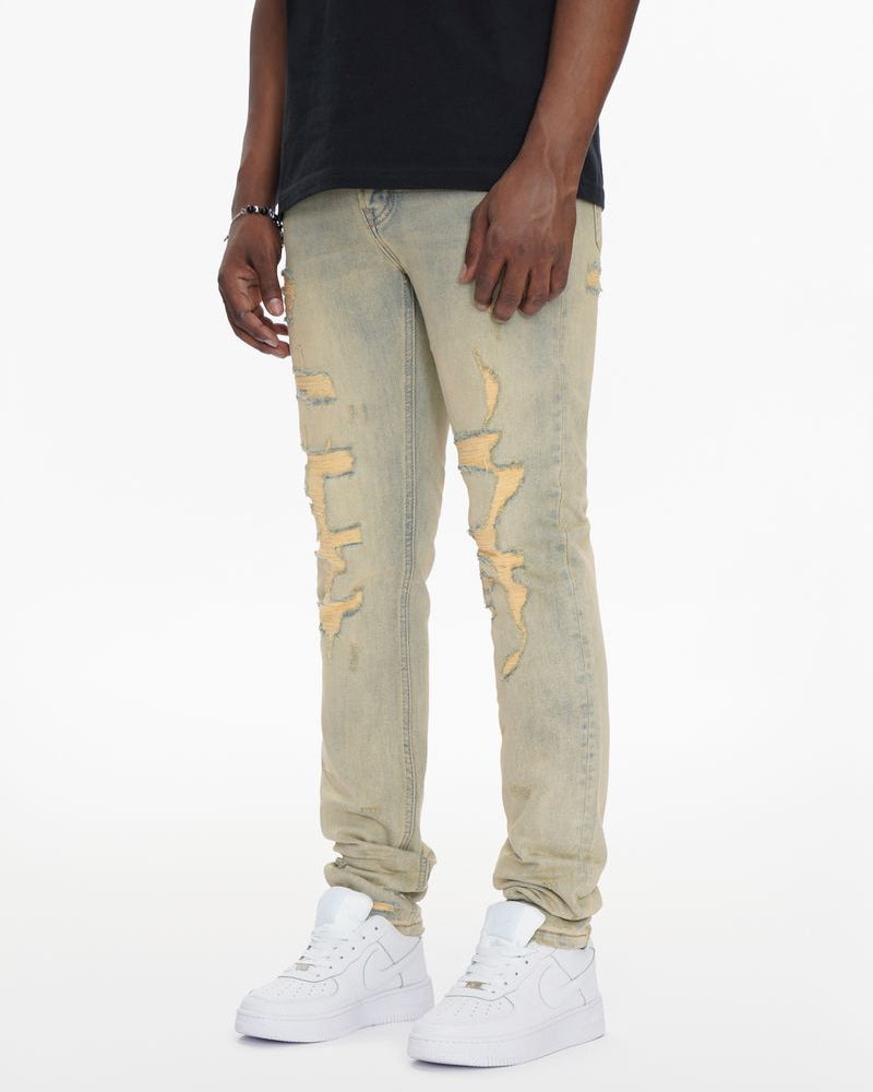 Person wearing beige distressed jeans and white sneakers on a white background