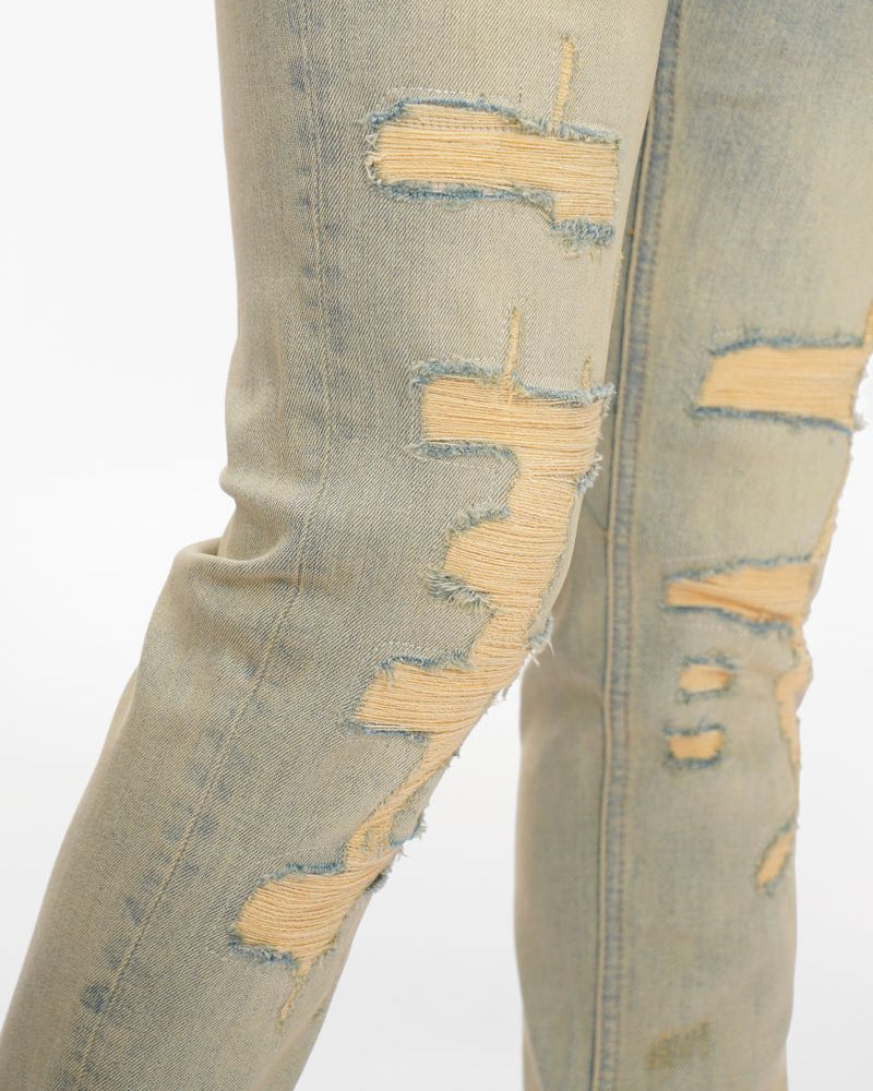 Distressed light green jeans on a white background