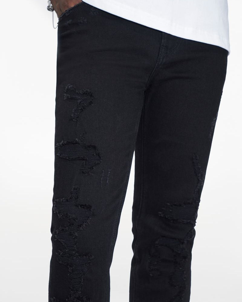 Black distressed jeans worn by a person on a white background