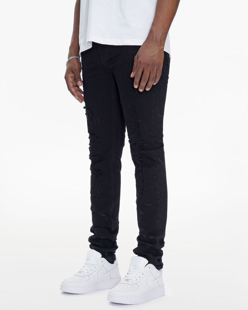 Person wearing black distressed jeans and white sneakers on a white background
