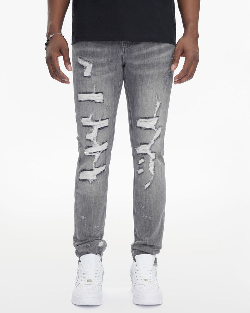 Person wearing gray distressed jeans on a white background