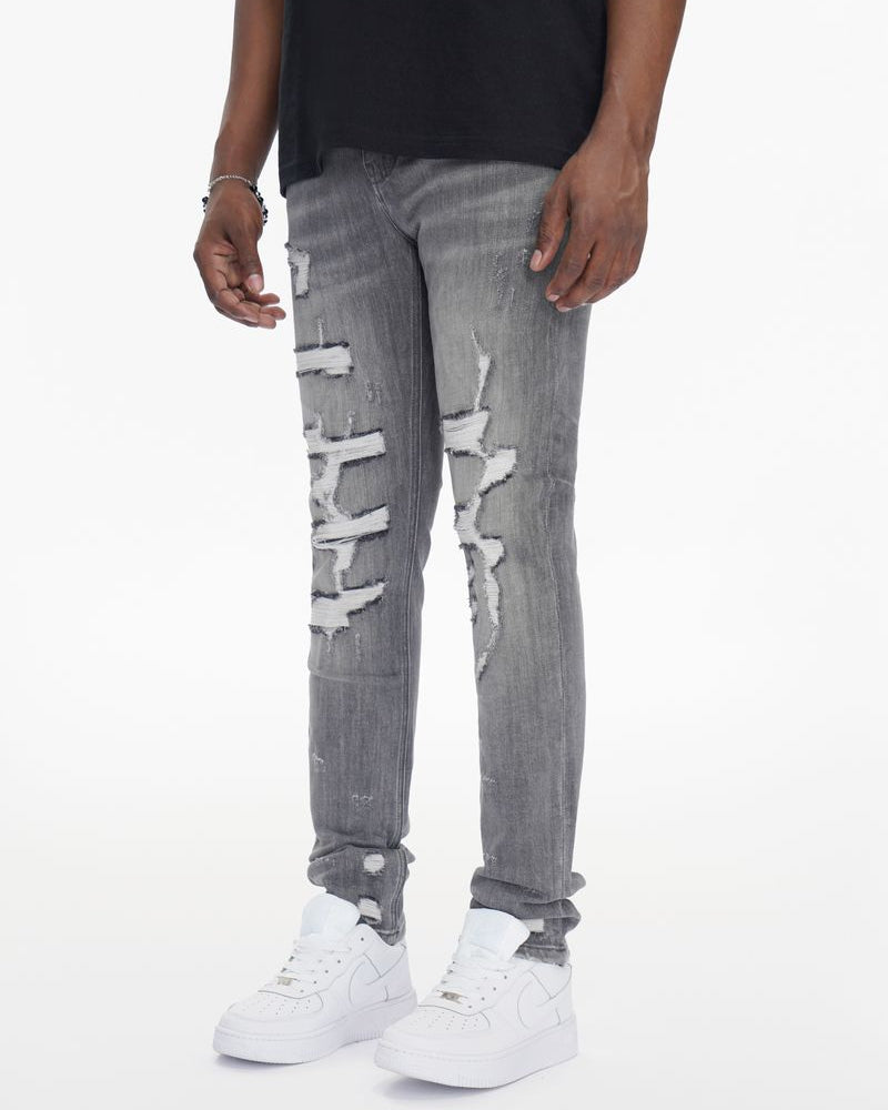 Person wearing gray distressed jeans and white sneakers on a white background