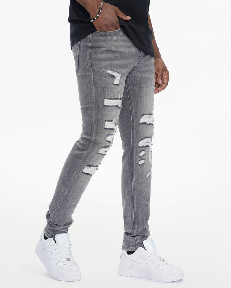 Person wearing gray distressed jeans and white sneakers on a white background