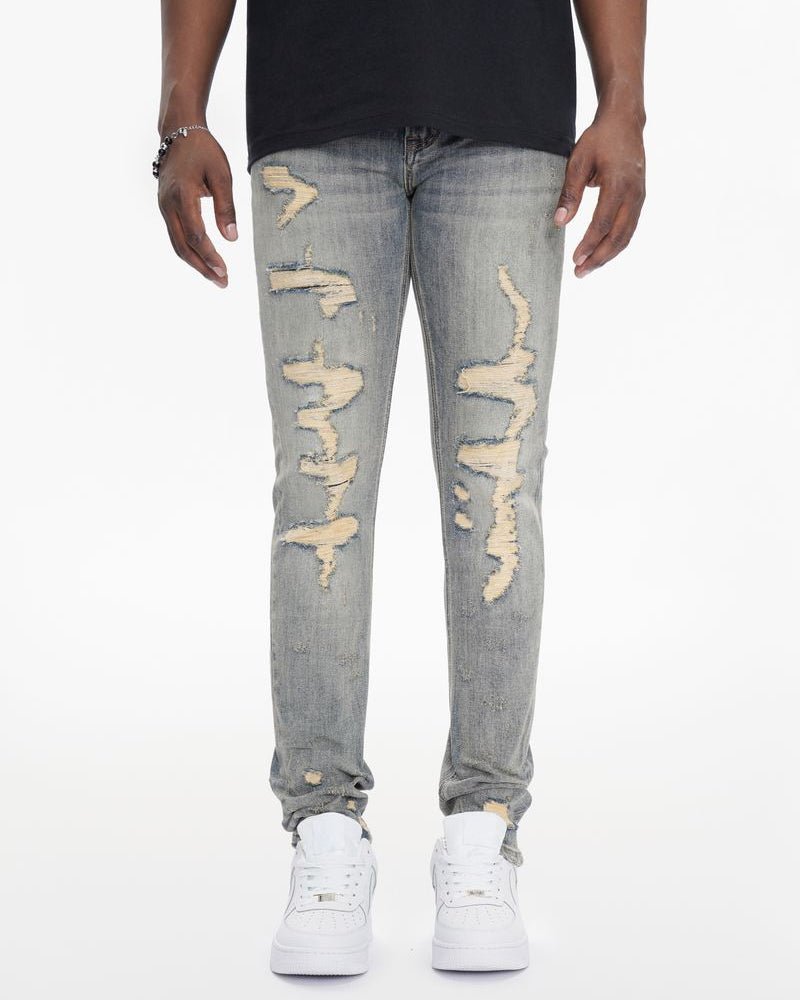 Person wearing distressed gray jeans and white sneakers on a white background