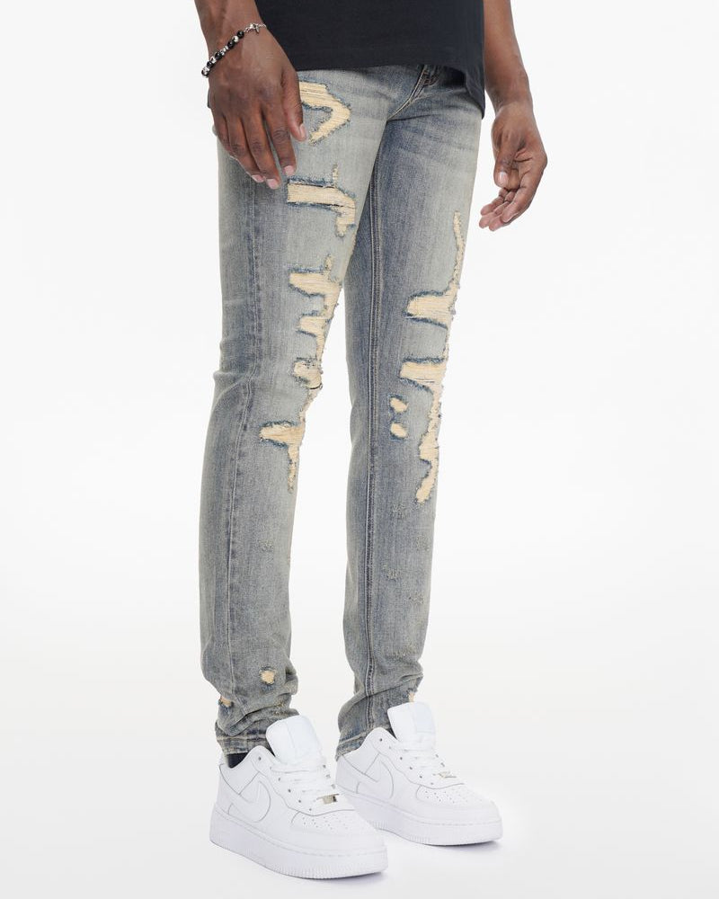 Person wearing light gray distressed jeans and white sneakers on a white background