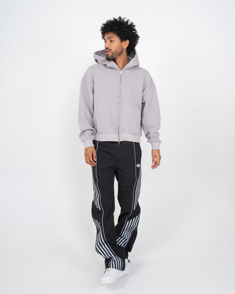 Man wearing a gray hoodie and black pants with white stripes on a white background