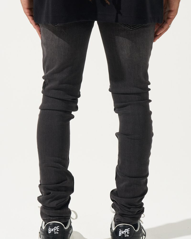 Person wearing black jeans and black sneakers on a white background