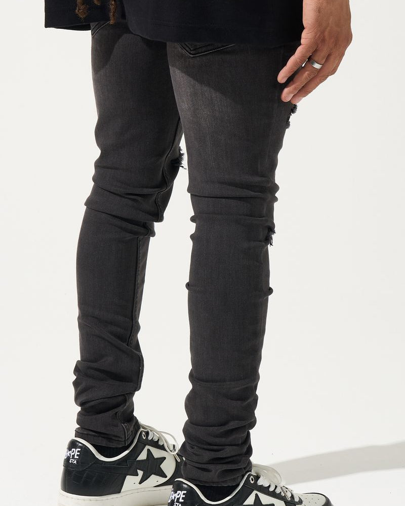 Person wearing black jeans and black sneakers with white star designs on a white background