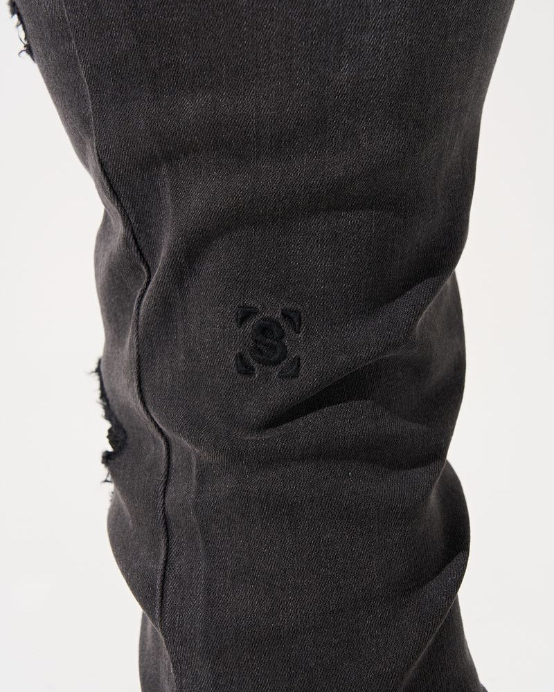 Close-up of black pants with a brand logo on a white background