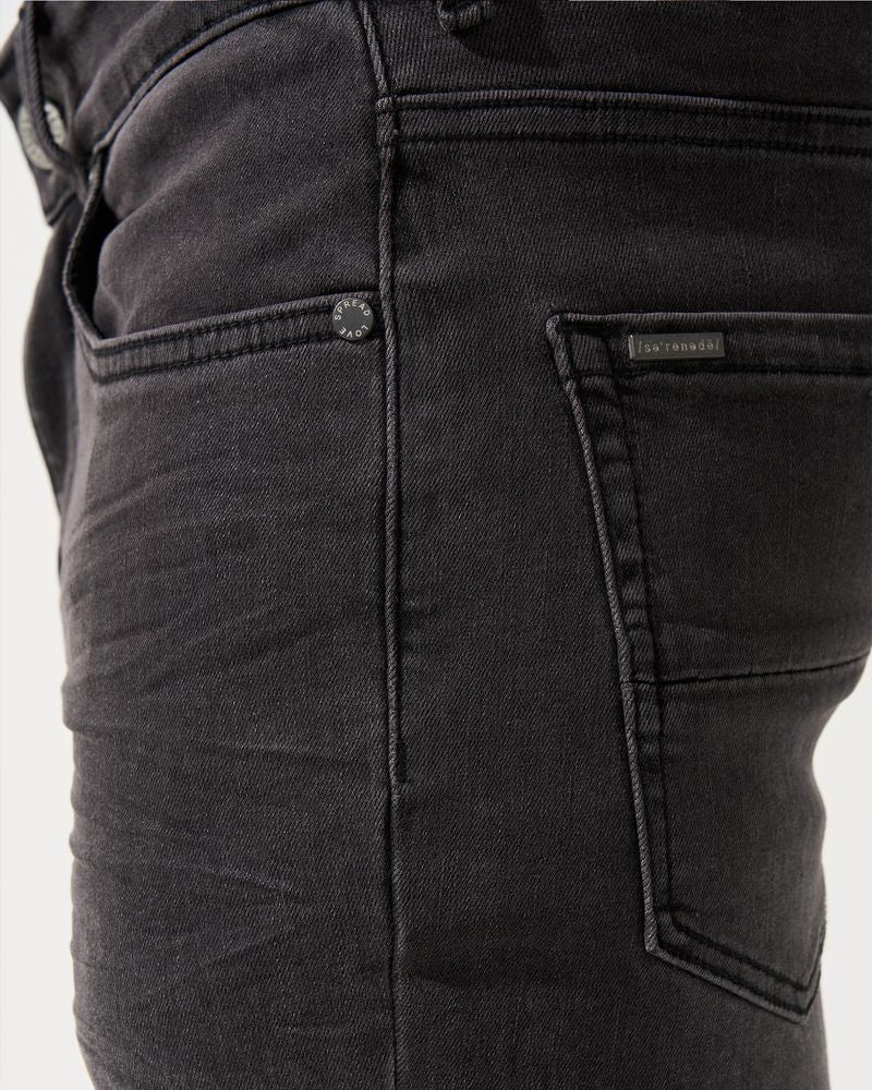 Close-up of black pants with a brand label on a white background
