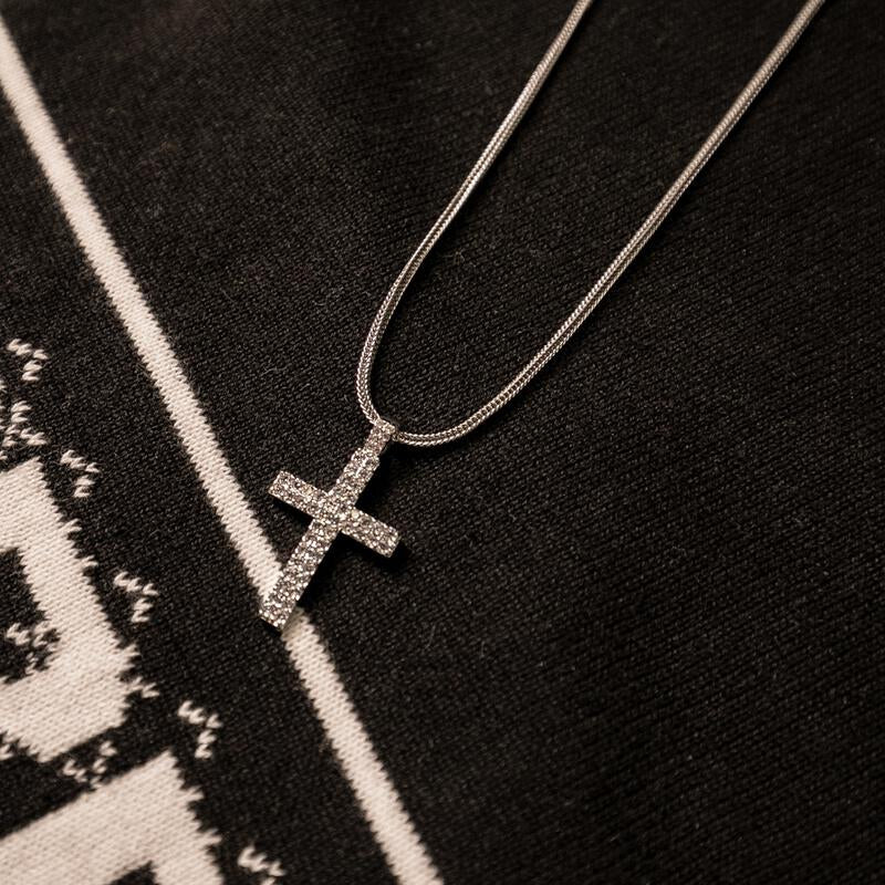 Silver cross necklace on a black background with white text