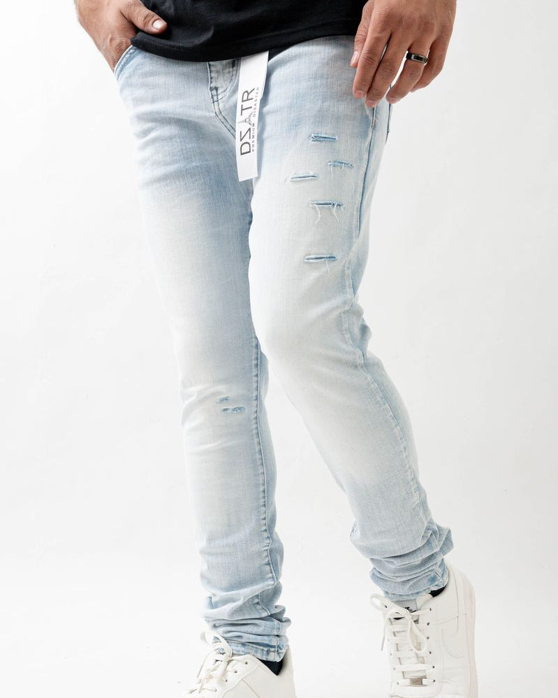 Person wearing light blue distressed jeans and white sneakers on a white background