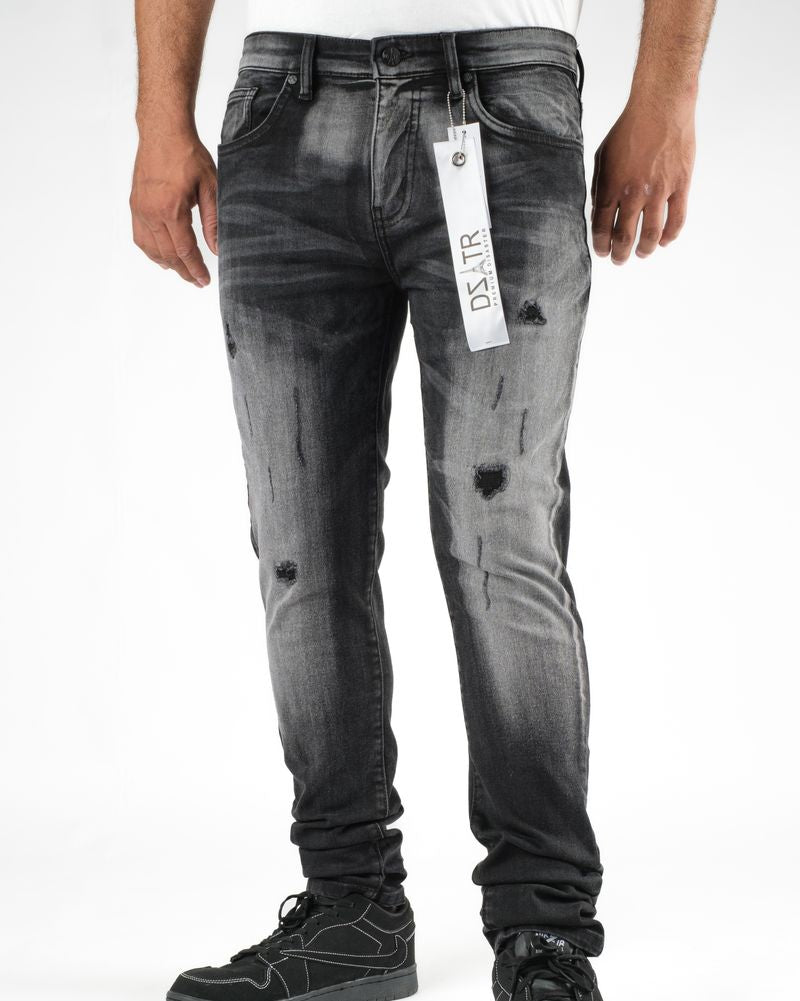 Person wearing distressed black jeans with a visible brand tag on a white background