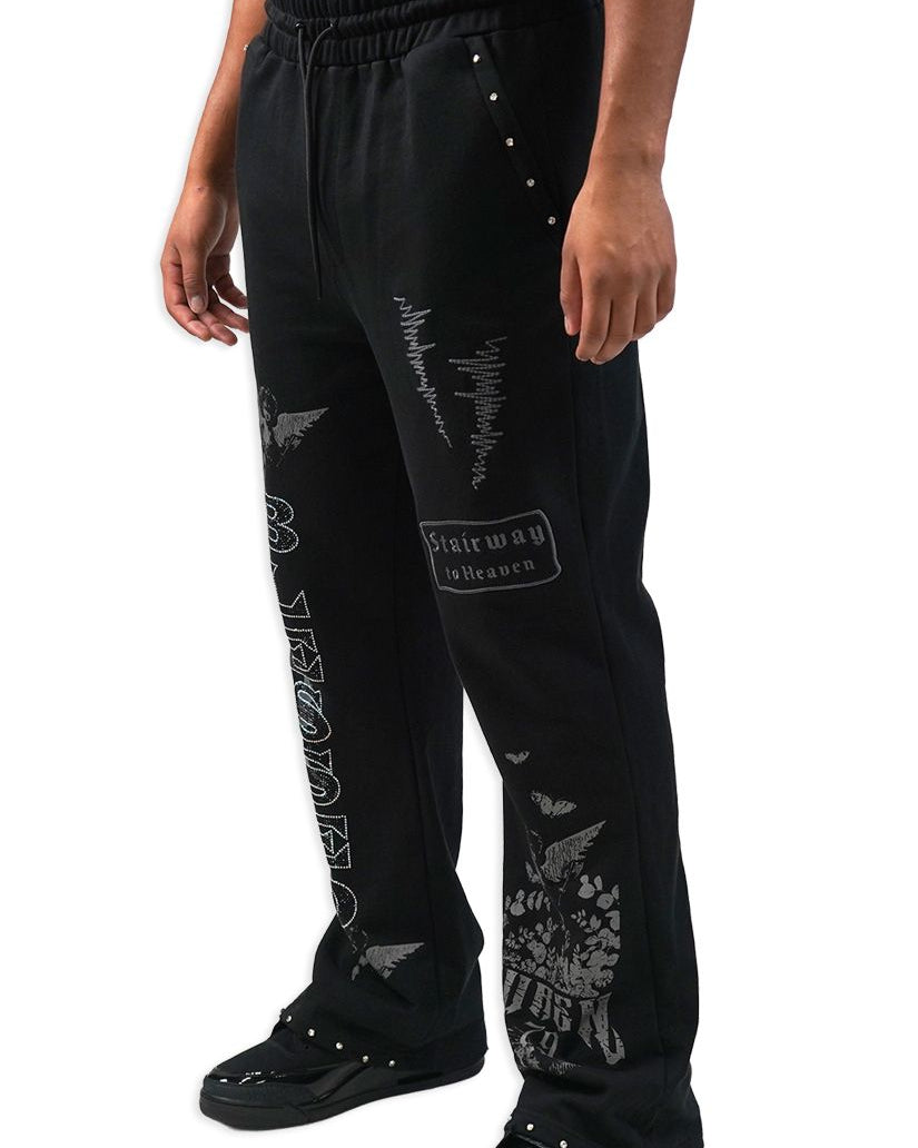 Black distressed pants with white text and graphics on a white background