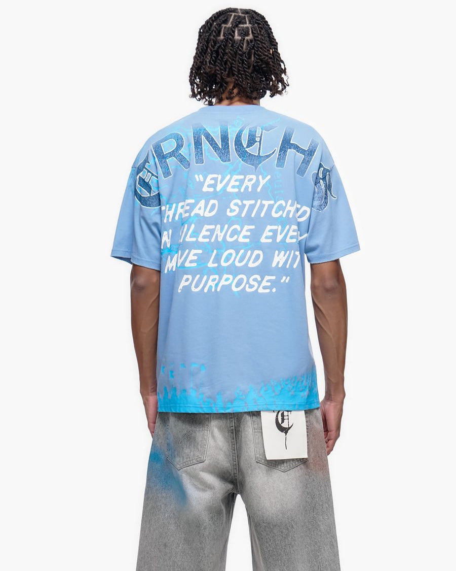 Person wearing a blue t-shirt with text on the back, standing against a white background