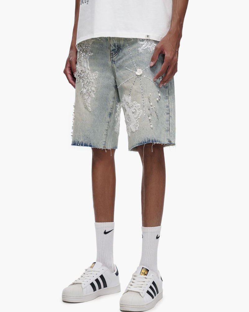 Person wearing light denim shorts with sequin details on a white background