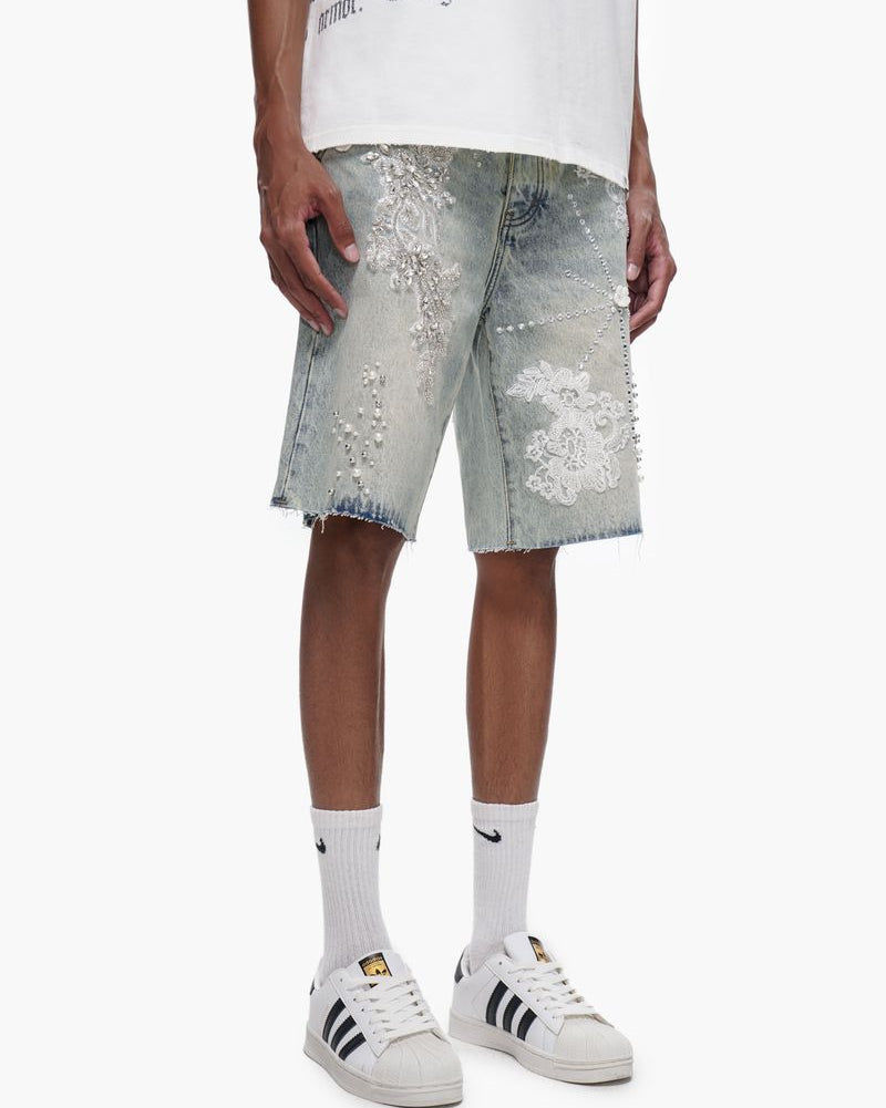 Person wearing distressed denim shorts with sequin embellishments on a white background