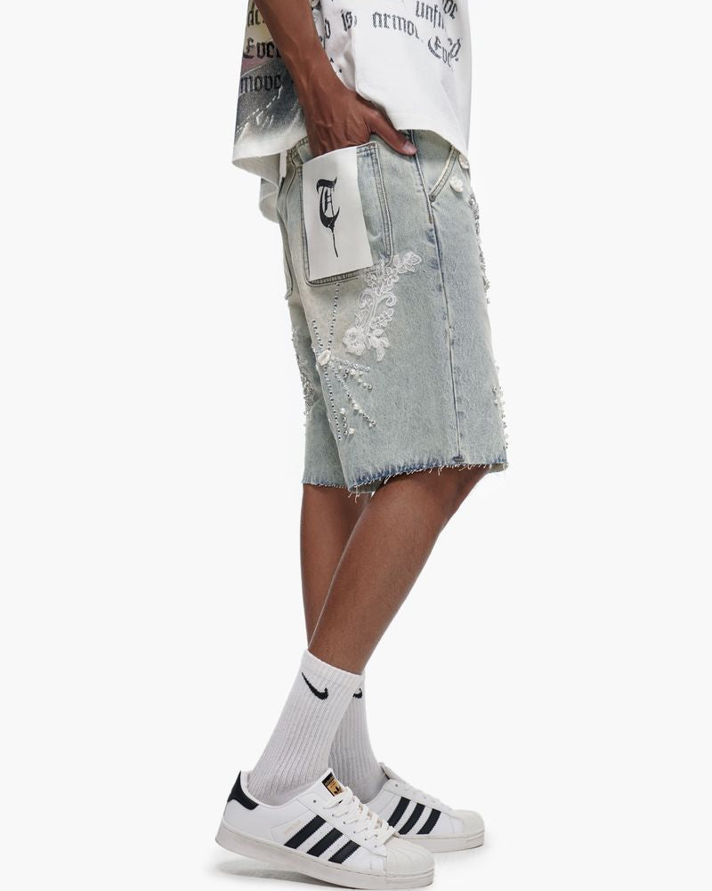 Person wearing light gray distressed denim shorts with a white background