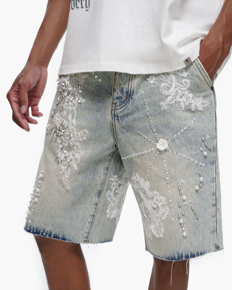Denim shorts with floral embroidery and a white t-shirt worn by a person on a plain background