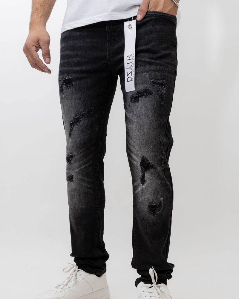 Person wearing black distressed jeans with a visible brand label on a white background