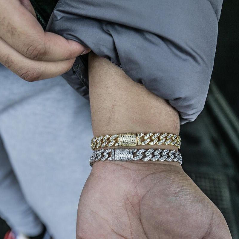 Gold and silver cuban link chain bracelets on a person's wrist with a dark background