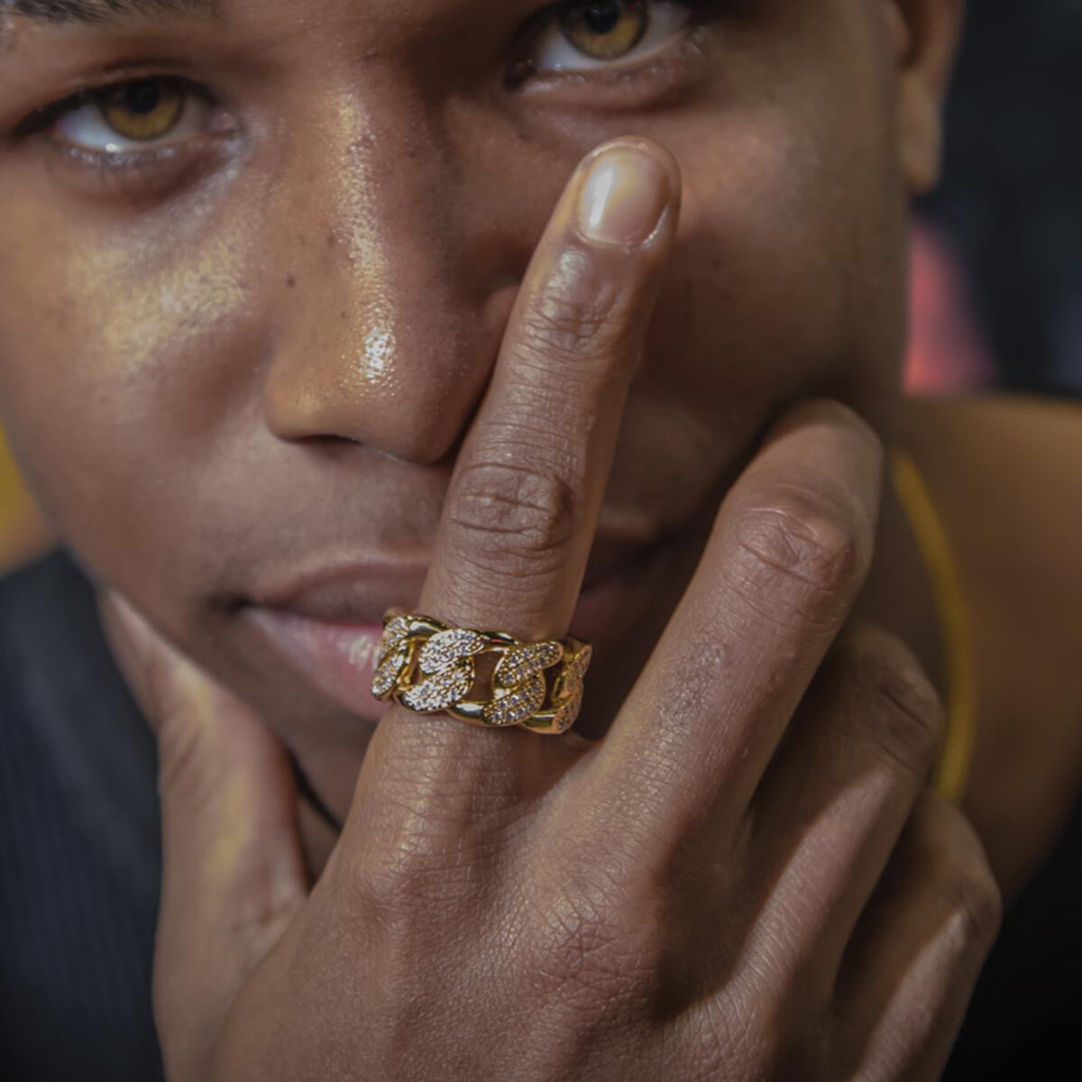 Close-up of a person wearing the gold studded cuban ring with a blurred background