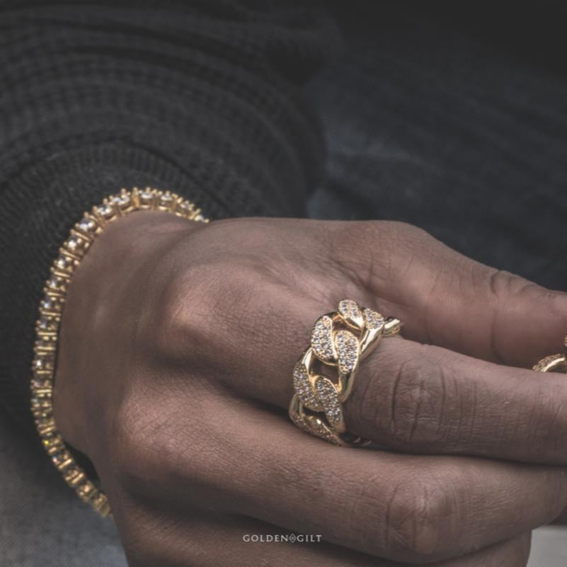 Close-up of a hand wearing the gold studded cuban ring with a blurred background