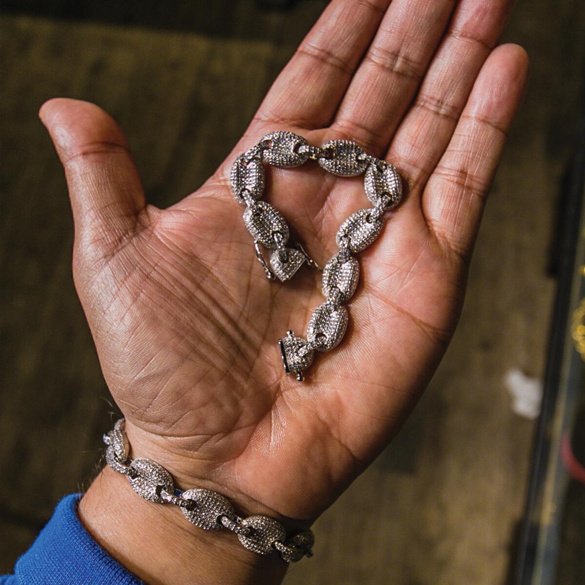 Hand holding the silver studded goochi bracelet with a blurred background