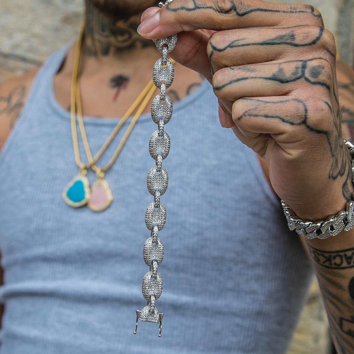 Person holding the silver studded goochi necklace with a detailed clasp, wearing a blue tank top.