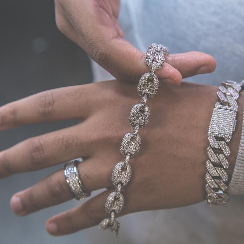 Person holding the silver studded goochi necklace with a detailed clasp, wearing a blue tank top.
