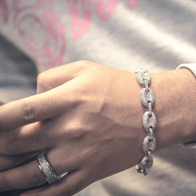 Person holding the silver studded goochi necklace with a detailed clasp, wearing a blue tank top.