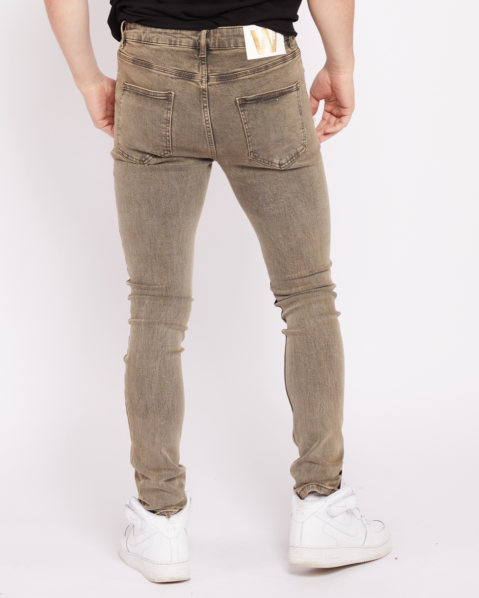 Person wearing brown jeans and white sneakers on a white background