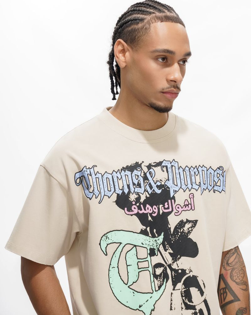 Man wearing a 'Thorns & Purposes' t-shirt with graphic design on a white background
