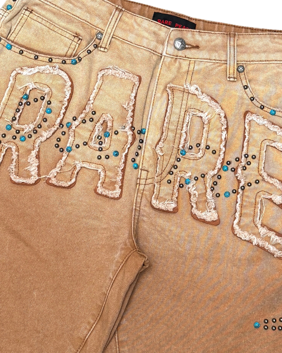 Brown pants with 'RARE' text in rhinestones on a beige background