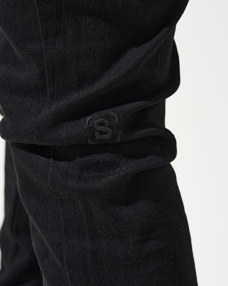 Close-up of black pants with a logo on a white background