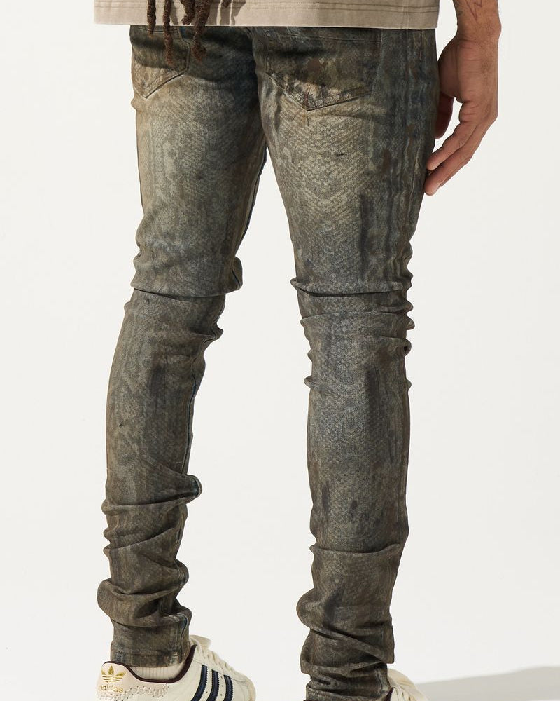 Person wearing distressed gray jeans and white sneakers with black stripes on a plain background