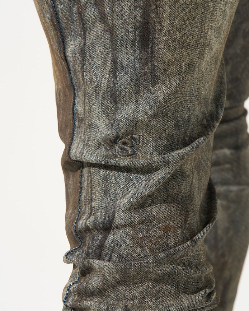 Close-up of a person wearing gray jeans with a visible brand logo on a white background