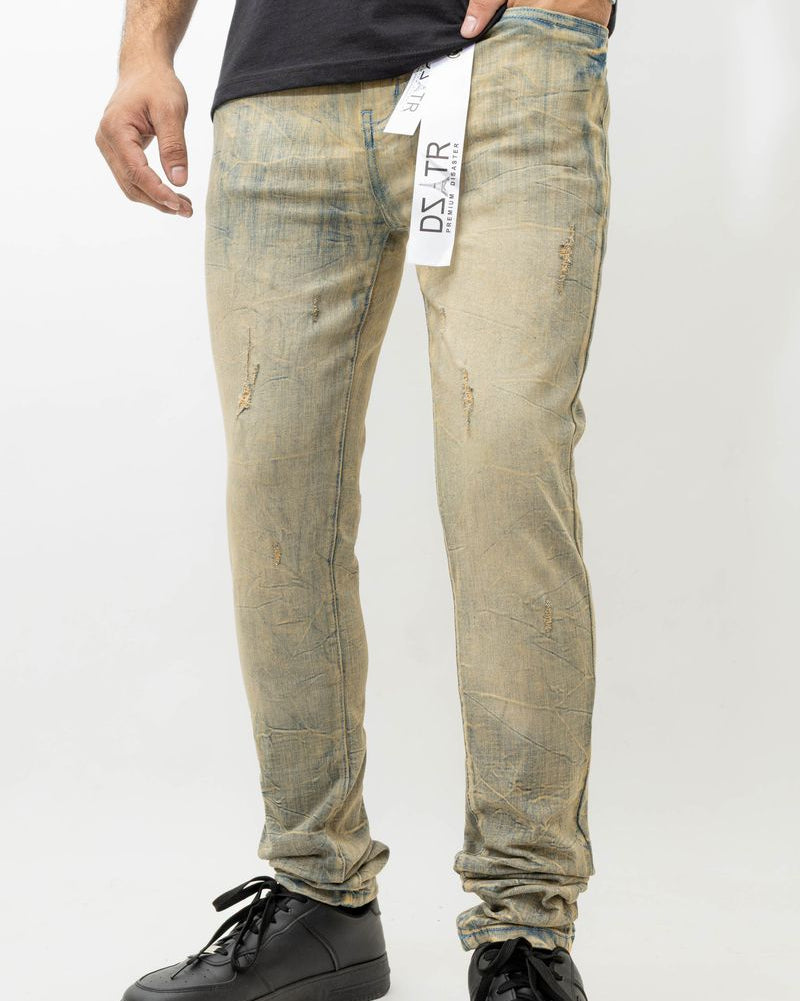 Person wearing distressed beige jeans with a visible brand label on a white background