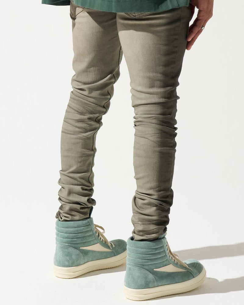 Person wearing beige pants and green shoes on a white background