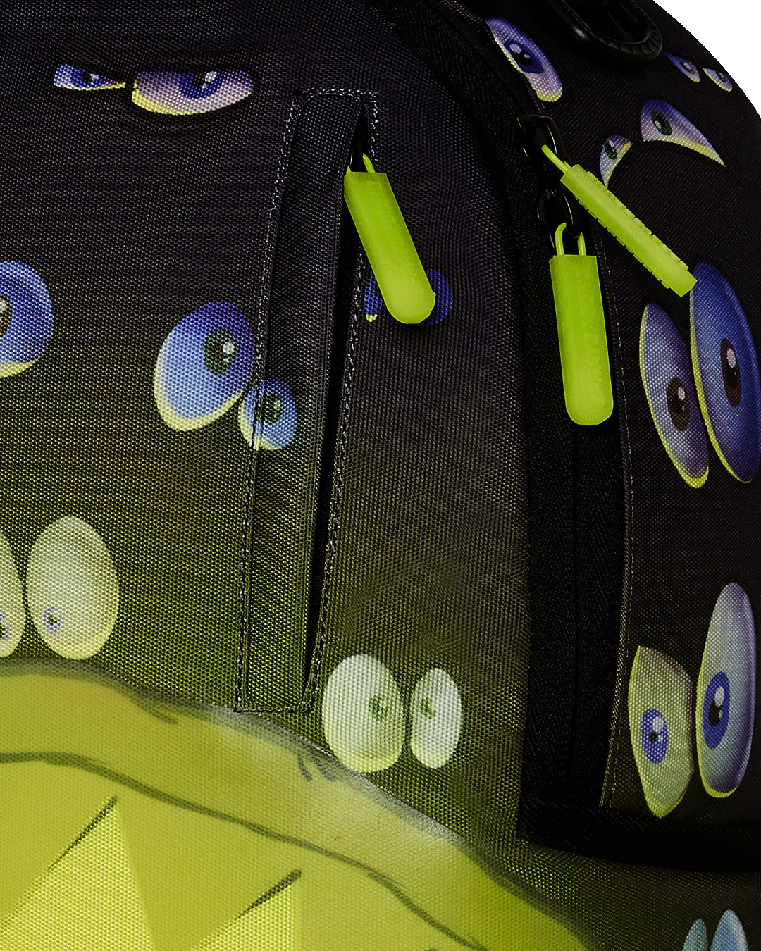 Close-up of a backpack with eye pattern and green zippers