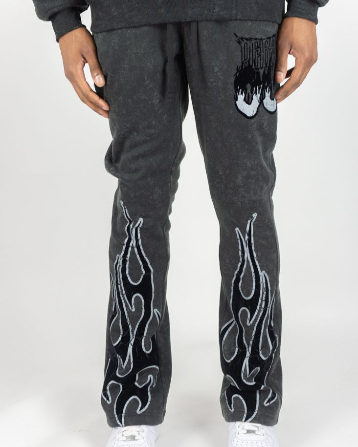 Person wearing dark gray sweatpants with white flame patterns on a white background