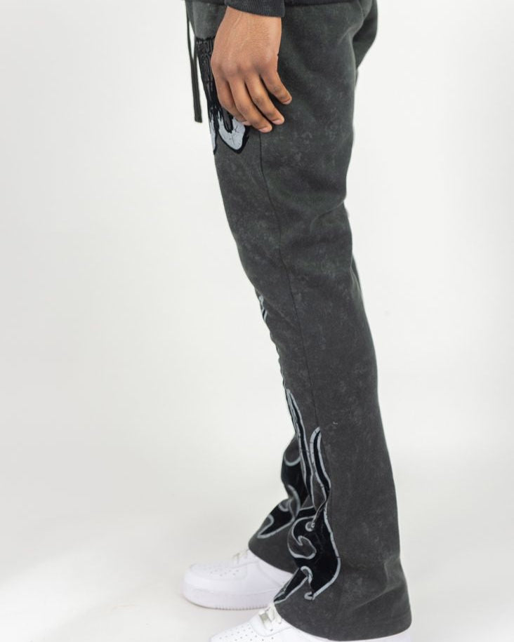 Person wearing dark gray pants with decorative elements on a white background