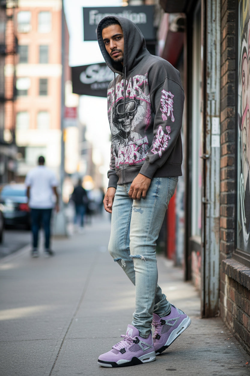 Person wearing a graphic hoodie and light blue jeans on a city street.