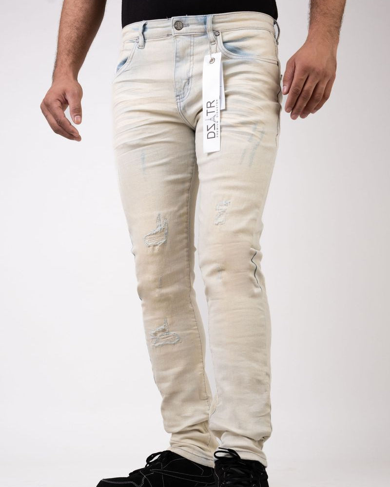 Beige distressed jeans with a brand tag on a white background