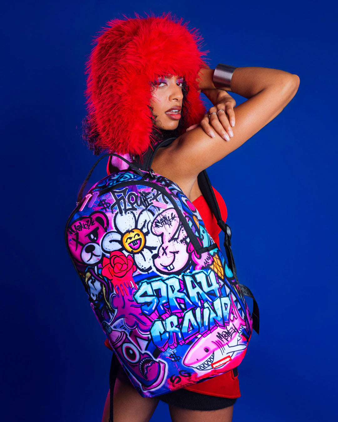 Person wearing a colorful backpack with graffiti-style design against a blue background