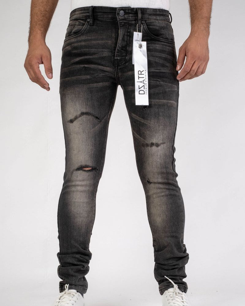 Person wearing black distressed jeans with a visible brand tag on a white background
