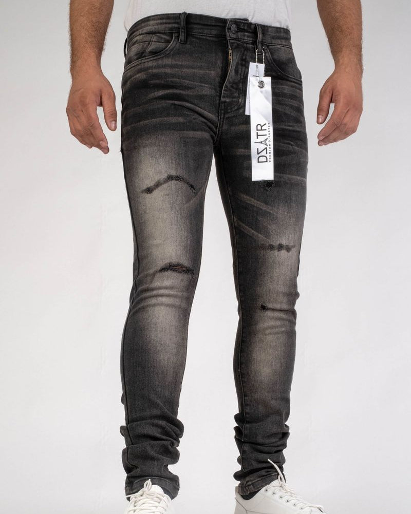 Person wearing black distressed jeans with a brand tag on a white background