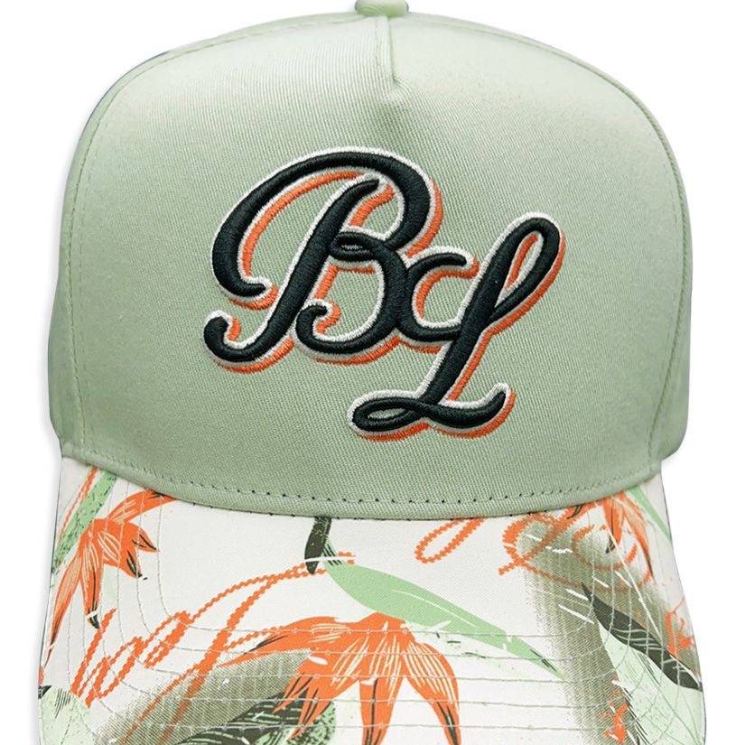 a sage green dad hat with a floral brim. The brand Blac Leaf embroidered the initials on the front face in complimenting thread.