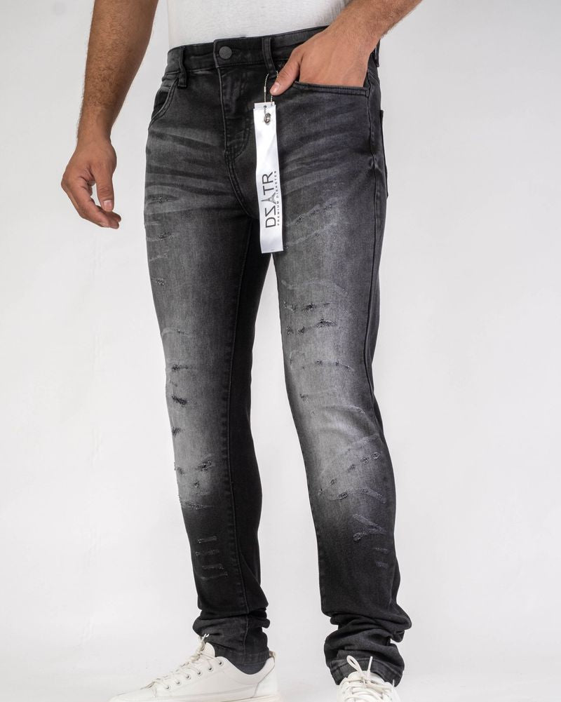 Person wearing black distressed jeans with a brand tag on a white background