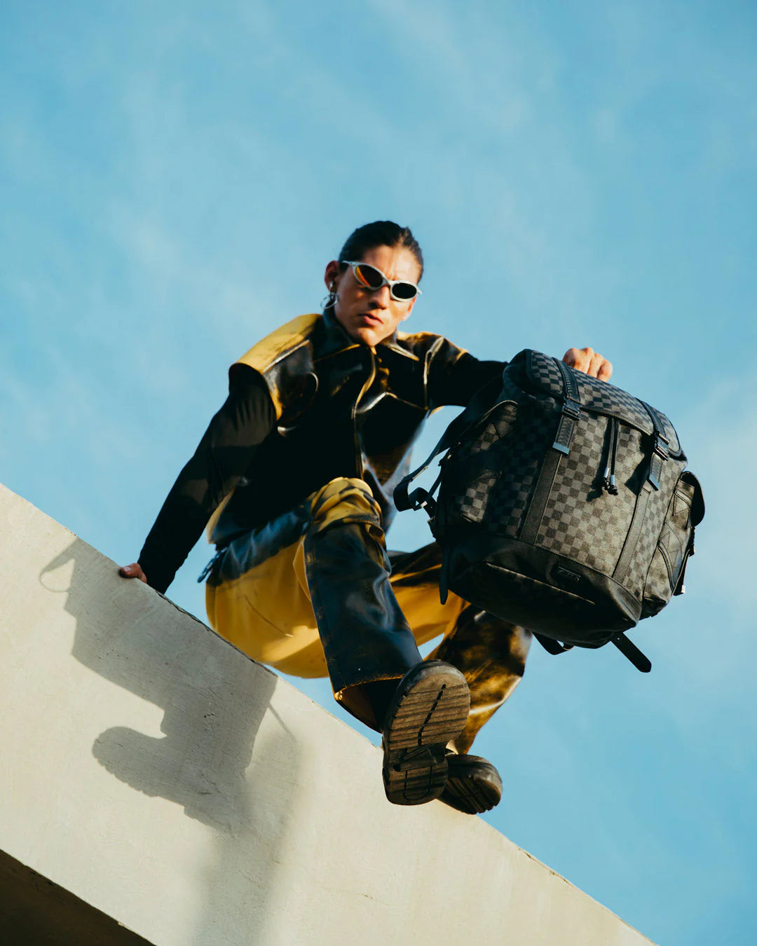 Person holding a backpack against a blue sky